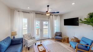 Ein modernes Wohnzimmer mit Sofa, Sessel, Couchtisch und Deckenventilator.