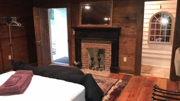 A bedroom with a bed, a fireplace, a mirror, and a door leading outside. - 2 of 3 GuestQuarters & 35 Min to U of Alabama (Eutaw)