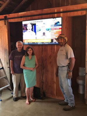 Three people standing in front of a television displaying a sports game.