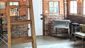 A rustic cabin interior with a wooden ladder, a stone fireplace, and a bar area. - Pecan Shelling House - 35 Mins to Univ of Alabama (Eutaw)