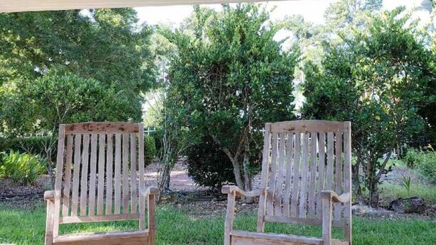 A wooden sign reading "The Pecan Sheltering House" above two rocking chairs in a covered outdoor area with a view of trees. - Pecan Shelling House - 35 Mins to Univ of Alabama (Eutaw)