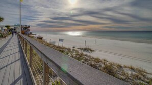 A wooden boardwalk leading to a beach with a clear view of the ocean and a flagpole with a flag. - Golf-course & water-view condo with central AC, shared pool,hot tub (Miramar Beach)