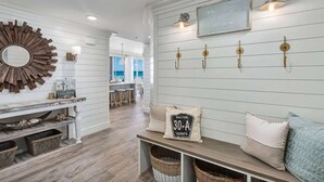 A room with a wooden bench, wall-mounted light fixtures, a decorative mirror, and a sign reading "WALTON 30-A COUNTY". - Stunning Beachfront condo with two pools, a hot tub, onsite gym and tennis/pickleball courts. (Santa Rosa Beach)