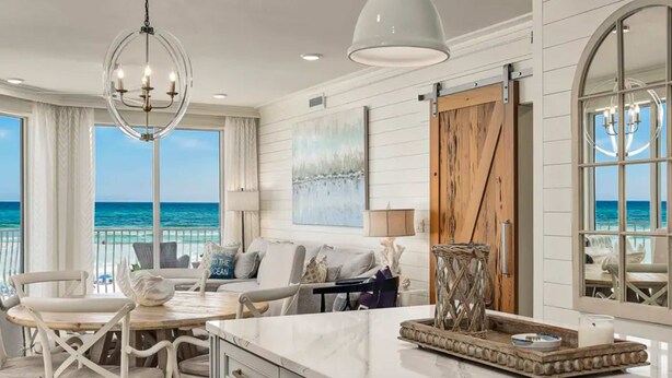 A spacious living area with a large window overlooking the ocean, a wooden door, and a marble island. - Stunning Beachfront condo with two pools, a hot tub, onsite gym and tennis/pickleball courts. (Santa Rosa Beach)