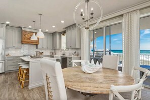 Una cocina moderna con armarios grises, una isla de madera y un comedor con sillas blancas y una mesa de madera.