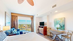 A hotel room with a large bed, a sofa, a desk, and a TV.