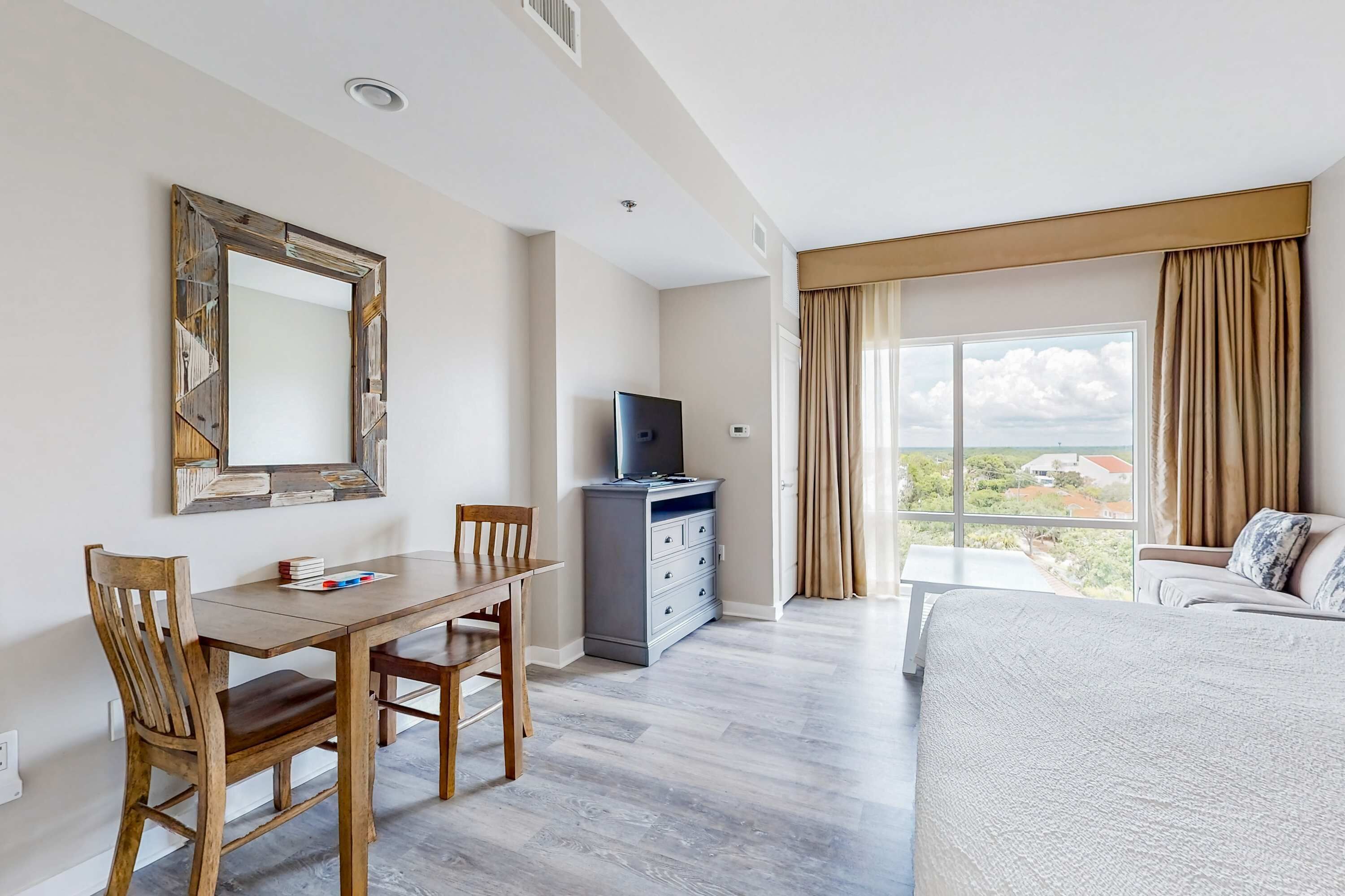 Ein Hotelzimmer mit Esstisch, Stühlen, Fernseher, Kommode und Bett.