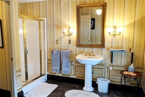 Une salle de bain avec un lavabo blanc, deux serviettes, un miroir et une petite table sur laquelle sont posés des articles de toilette.