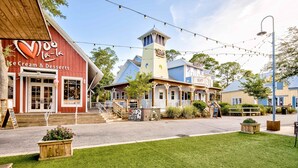 A building with a red facade and a sign for 'Ice Cream & Desserts'. - Ground-floor condo with patio, central AC, shared pool, & tennis (Miramar Beach)