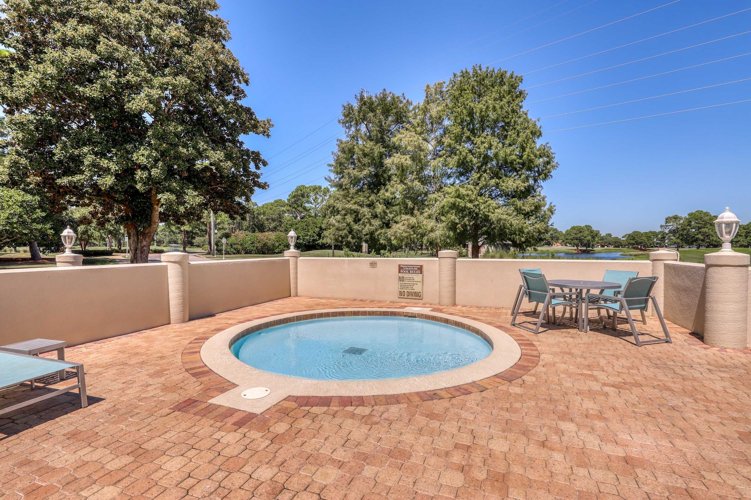 A swimming pool with a brick patio, outdoor seating, and a 'No Diving' sign.