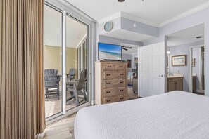 A hotel room with a bed, a dresser, a television, and a sliding glass door leading to a balcony. - Inviting 5th Floor Condo On Okaloosa Island Gulf-Front Views Beach Chairs (Fort Walton Beach)