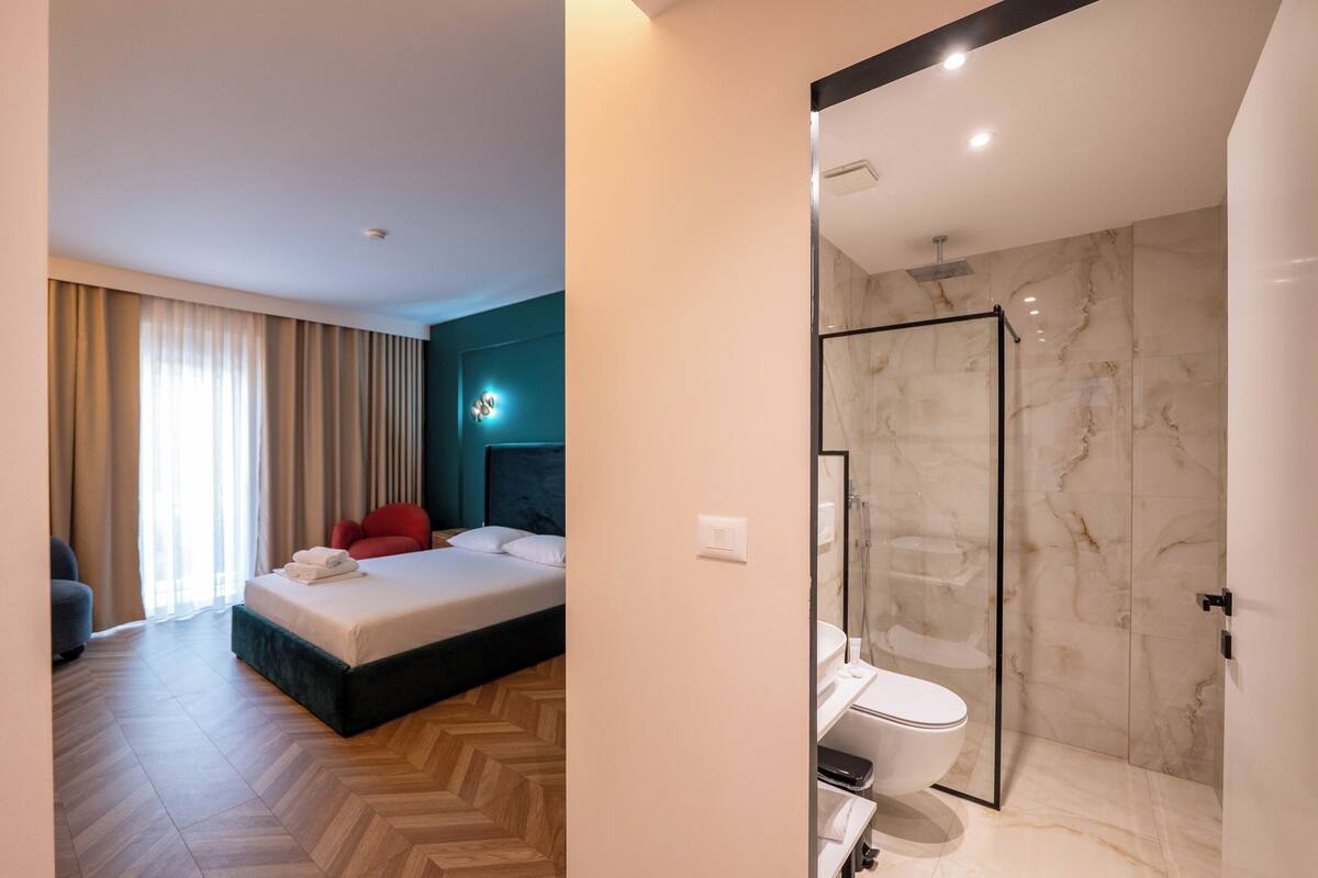 A hotel room with a bed, a shower, and a bathroom.