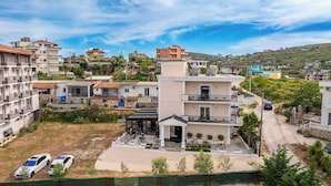 Un edificio a più piani con balconi, un cortile lastricato e uno sfondo collinare.