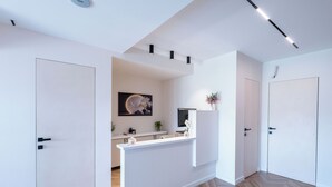 Una hall moderna di un hotel con una reception, un'opera d'arte di grandi dimensioni e un pavimento in legno a spina di pesce.