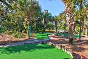 Een golfbaan met groene fairways, zandbunkers en een houten hek.