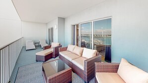 Un balcone con mobili in vimini, una porta in vetro e vista sulla città.