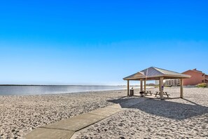 Una playa con un pabellón techado, mesas de picnic y una vista despejada del océano.