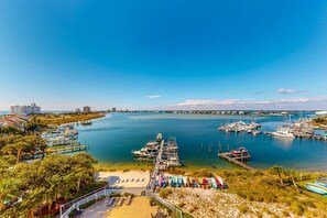 A marina with boats docked, a pier, and a beach area with umbrellas. - Sunlit & tropical beachfront condo with pool, gym, balcony views (Pensacola Beach)