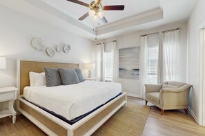 A bedroom with a bed, a chair, a nightstand, a ceiling fan, and a window with curtains. - Beachy retreat within easy walking distance to pool, beach access & restaurants (Port St. Joe)