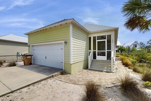 Une maison de plain-pied avec un garage, une véranda et une allée gravillonnée.