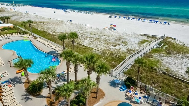 Een resort met een zwembad, een strand en palmbomen.