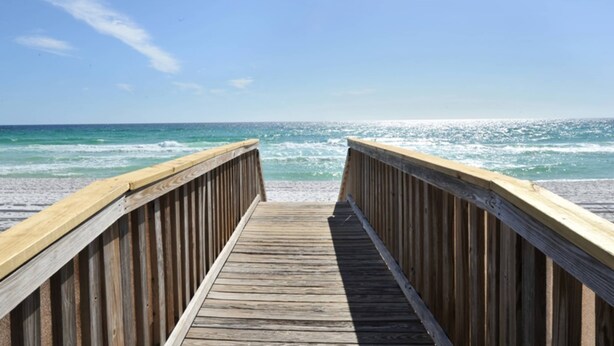 Un muelle de madera que conduce a una playa con olas.