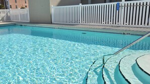 Una piscina cristalina con una cerca blanca y una escalera de acceso.
