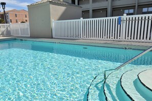 Ein klarer Swimmingpool mit weißem Zaun und einer Poolleiter.