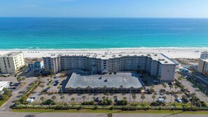 A multi-story hotel with a parking lot, beach view, and a pool area. - Gulf-front home with balcony, ocean views, pool and beach access (Fort Walton Beach)