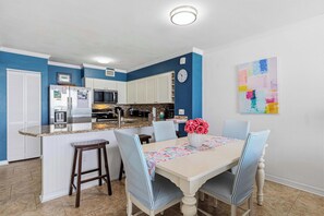 A kitchen with white cabinets, a stainless steel refrigerator, and a granite countertop. - Gulf-front home with balcony, ocean views, pool and beach access (Fort Walton Beach)