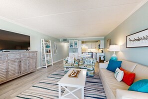 A living room with a sofa, armchairs, a coffee table, and a TV stand. - Sunlit Gulf-front condo with gorgeous water views, pool, balcony, & tennis court (Fort Walton Beach)