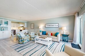 A modern living room with a sofa, coffee table, and a dining area with chairs. - Sunlit Gulf-front condo with gorgeous water views, pool, balcony, & tennis court (Fort Walton Beach)