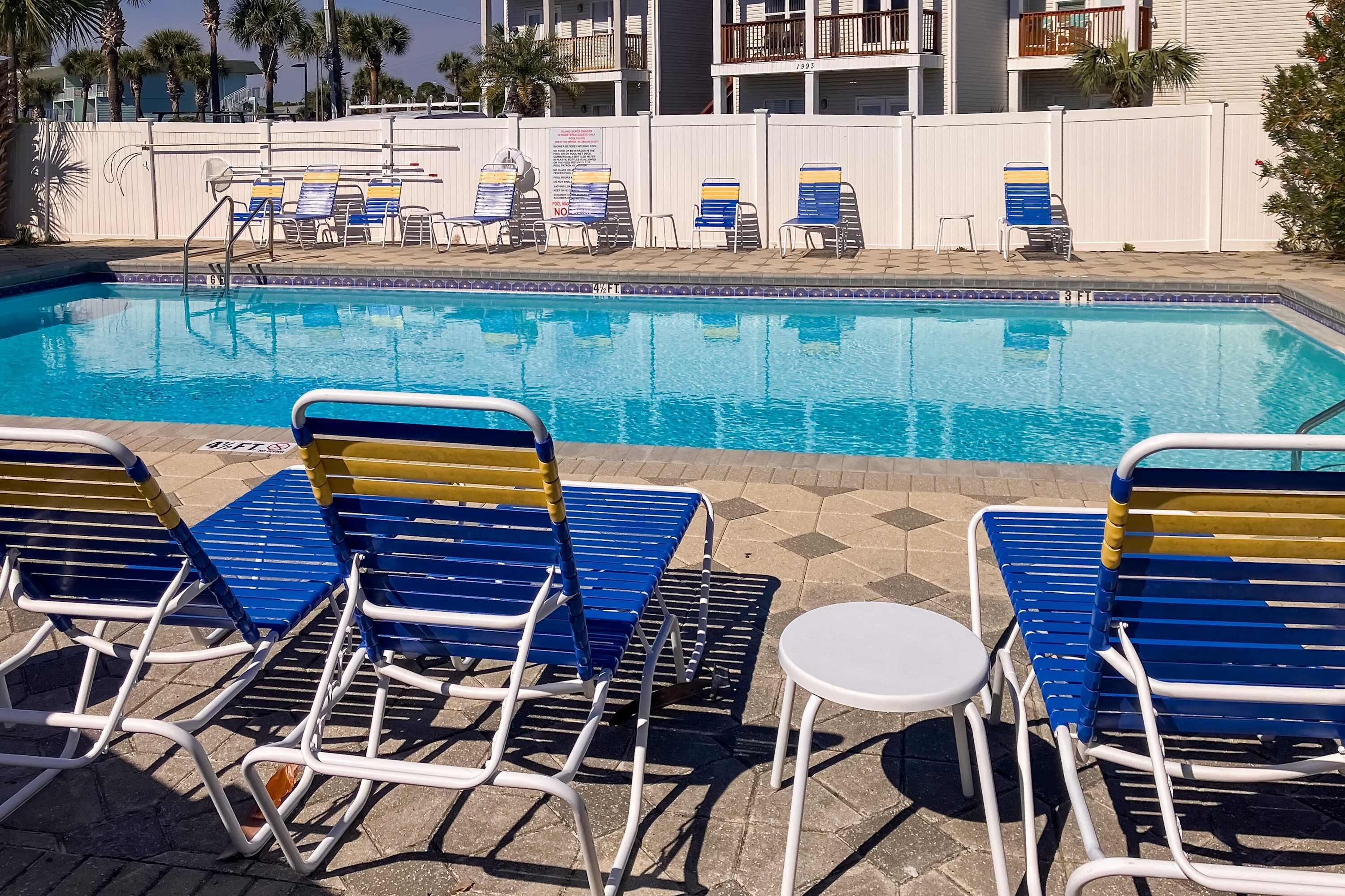 Une piscine avec des chaises longues et une table blanche.