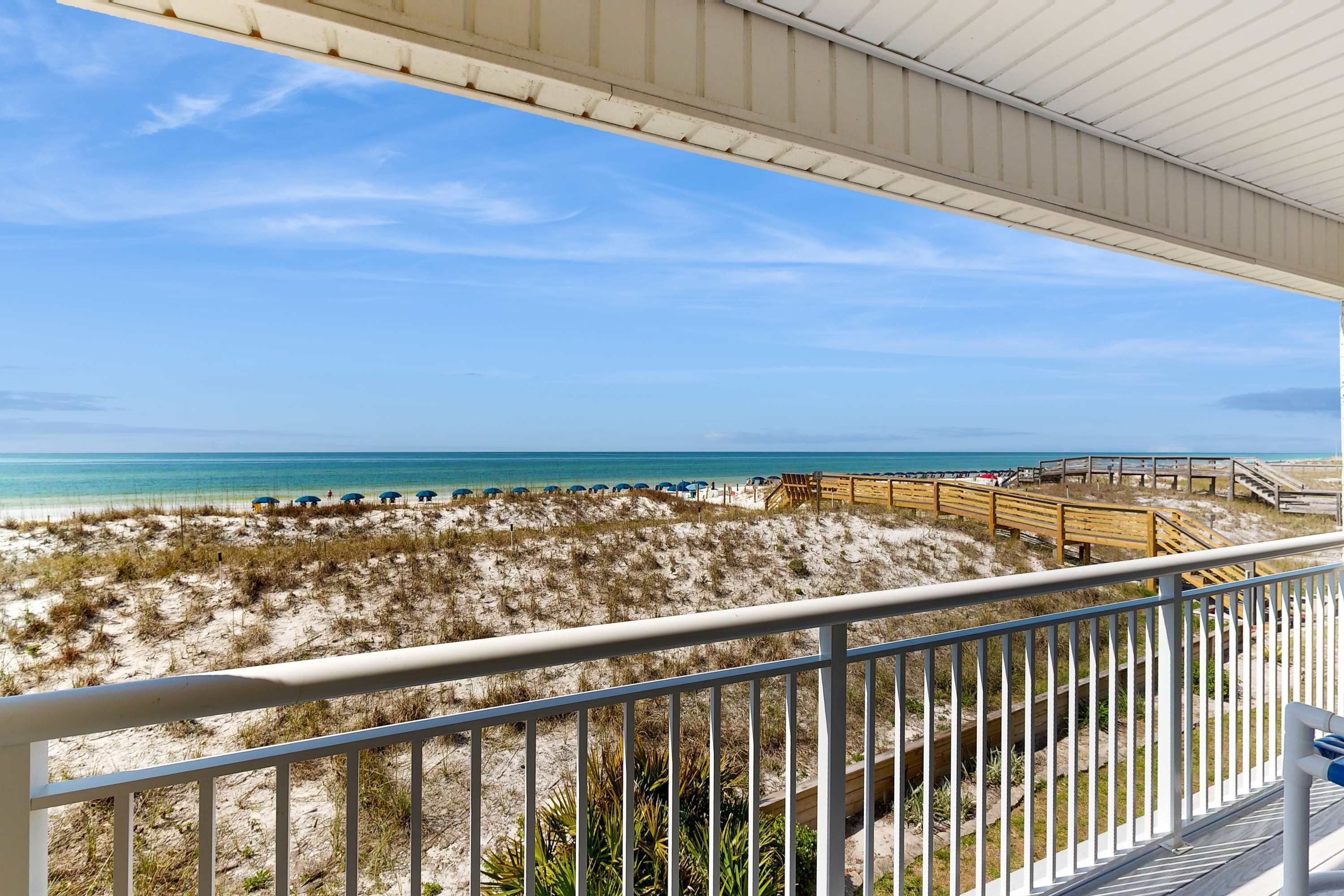 Une vue sur la plage depuis un balcon doté d’une terrasse en bois et d’une rambarde.