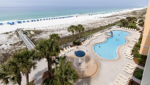 Een resort met een zwembad, uitzicht op het strand en ligbedden.