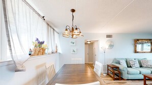 Ein Essbereich mit Holztisch, weißen Stühlen und einer Hängelampe.