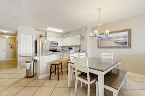 A modern kitchen with white cabinets, a granite countertop, and a dining area with a table and chairs. - Coastal condo with Gulf views, Shared pool, washer and dryer, Wifi (Fort Walton Beach)