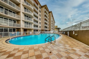 A swimming pool surrounded by a multi-story building with balconies. - Coastal condo with Gulf views, Shared pool, washer and dryer, Wifi (Fort Walton Beach)