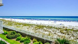Blick auf einen Strand mit blauem Himmel, sandigem Ufer und einigen Sonnenschirmen.