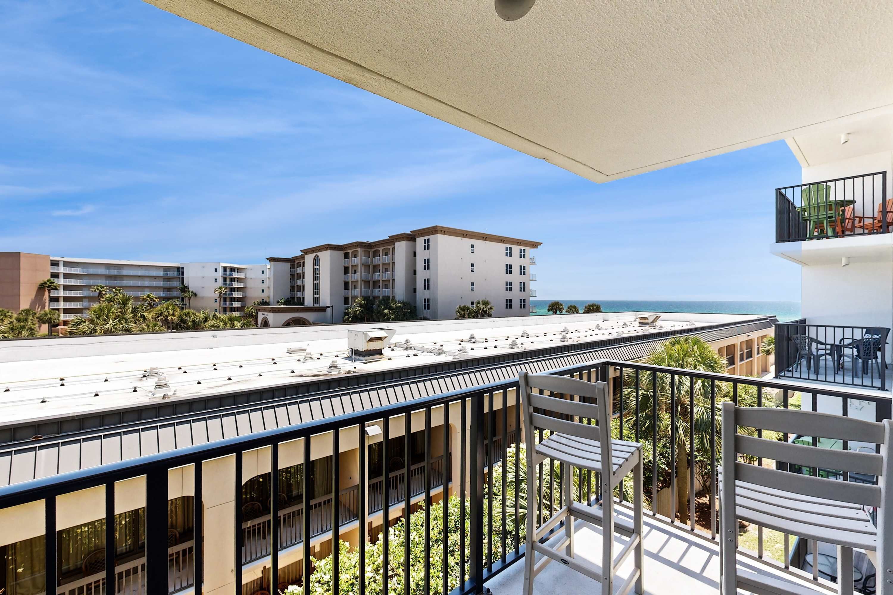 A balcony with a view of a building and the sea.