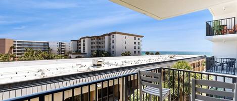A balcony with a view of a building and the sea.