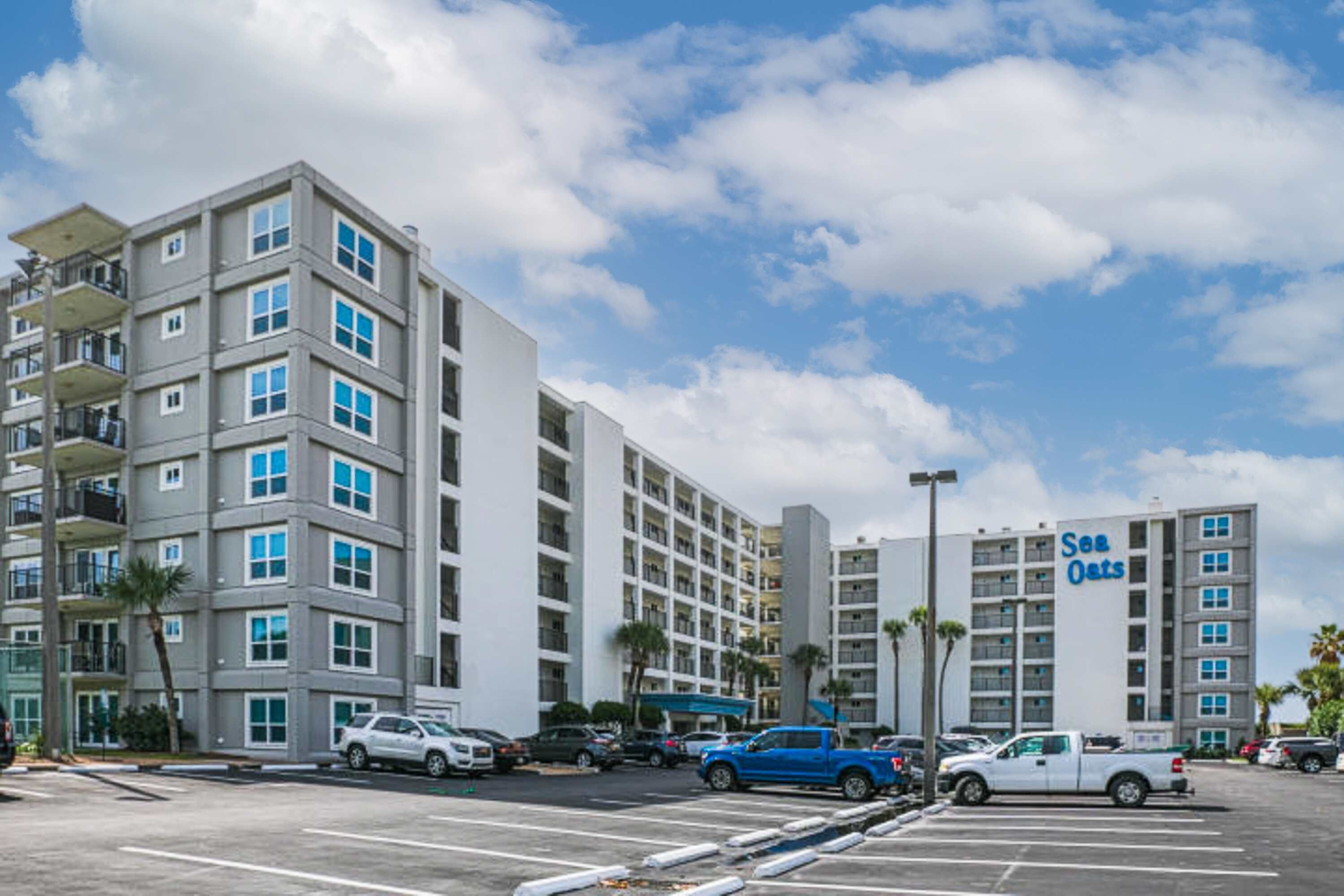 Et hotel med flere etager og en parkeringsplads foran.