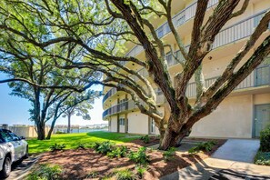 A multi-story building with balconies, a paved driveway, and a well-maintained lawn. - Bright, second-floor studio with high-speed WiFi & pool view - walk to the bay (Fort Walton Beach)