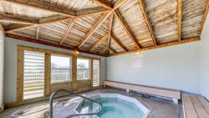 A hot tub in a room with wooden beams, large windows, and a bench. - Sea Oats 708 - 7th floor condo in beachfront complex with pool, Gulf view, W&D, & fast WiFi (Fort Walton Beach)