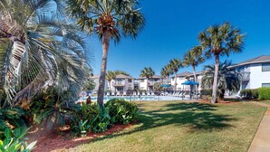 Ein Resort mit Swimmingpool, Palmen und einem gepflegten Rasen.