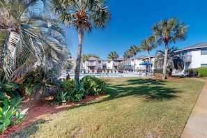 A resort with a swimming pool, palm trees, and a well-maintained lawn. - Coastal condo with a pool, patio, washer&dryer, & central AC - easy beach access (Miramar Beach)