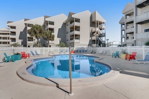 A swimming pool with lounge chairs and a white fence. - Condo with partial bay view, onsite fishing dock, beach access, & shared pool (Pensacola Beach)
