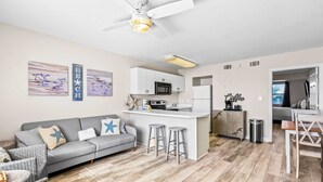 Um apartamento moderno com sofá cinzento, ilha de cozinha e banquetas.