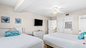 Quarto com duas camas, ventilador de teto, televisão e uma porta com janela.