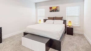 A bedroom with a bed, bedside tables, a nightstand, a wall-mounted artwork, and a window with blinds. - Gorgeous coastal home with plenty of space, close to everything - dog friendly (Gulf Breeze)
